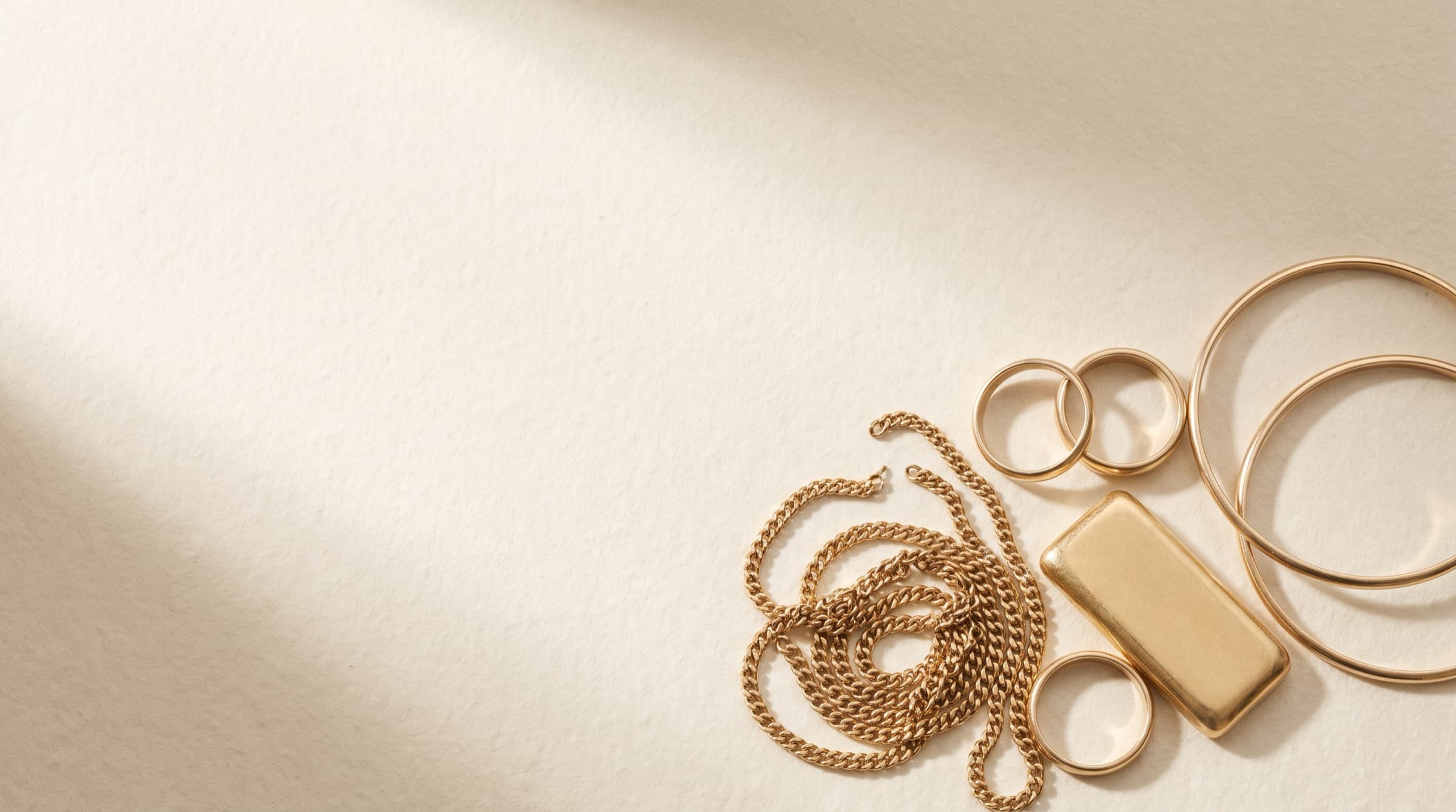 Scrap gold for purchase: chains, rings, bangles and a gold bar on a light surface